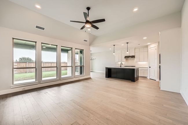 Unfurnished living room featuring vaulted ceiling, a sink, light wood finished floors, visible vents, and a ceiling fan | Image 4