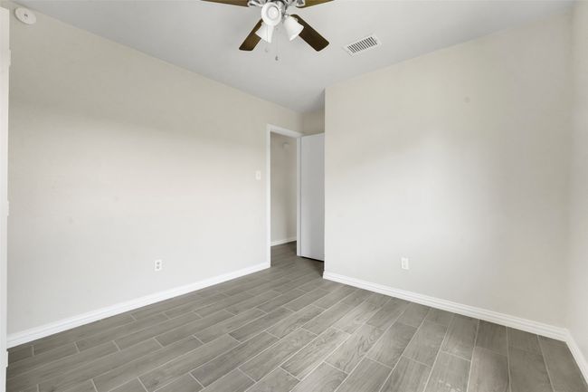 Unfurnished room with wood finished floors, ceiling fan, and a smoke detector | Image 12