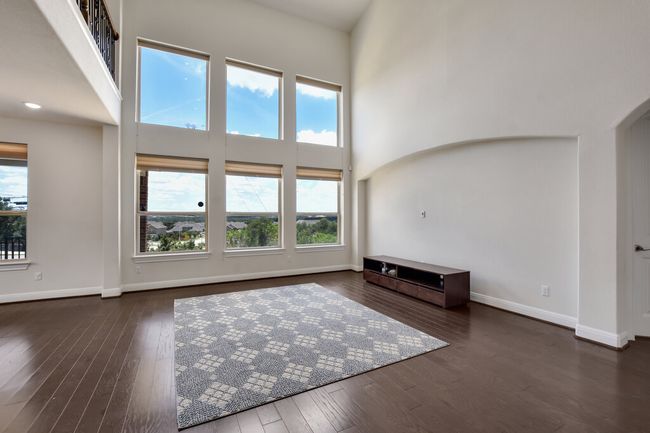 Unfurnished living room with a high ceiling, wood-type flooring, and arched walkways | Image 17