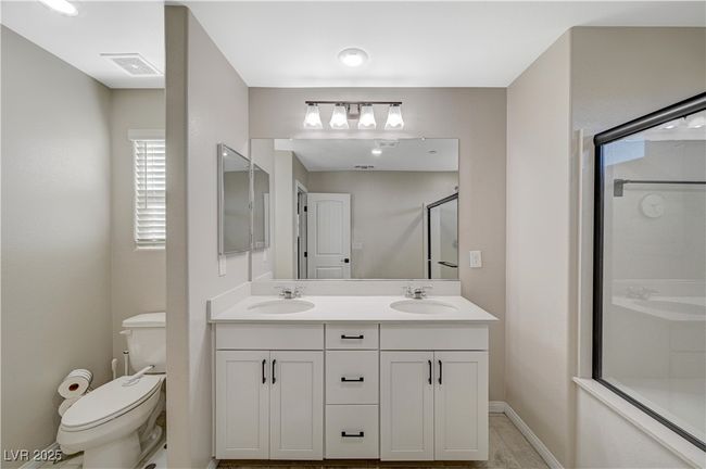 Bathroom with a shower with shower door, toilet, double vanity, and baseboards | Image 41