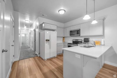 Kitchen featuring pendant lighting, appliances with stainless steel finishes, kitchen peninsula, sink, and light wood-type flooring | Image 3