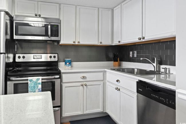Kitchen featuring white cabinets, a sink, backsplash, and appliances with stainless steel finishes | Image 14