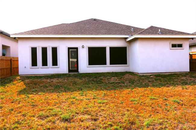 Rear view of property featuring stucco siding, a shingled roof, fence, and a yard | Image 22