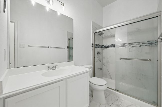Bathroom featuring a marble finish shower, toilet, vanity, and marble finish floors | Image 7