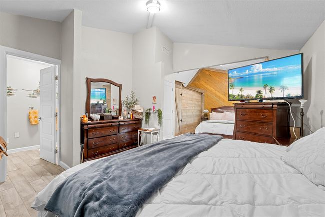 Bedroom with wood finished floors, visible vents, baseboards, and vaulted ceiling | Image 20