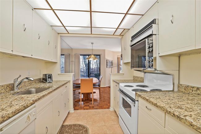 Kitchen featuring decorative light fixtures, white appliances, light parquet flooring, white cabinets, and sink | Image 14
