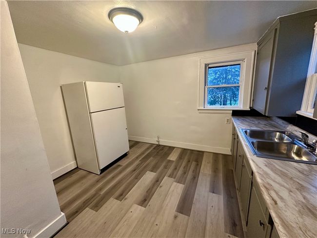 Kitchen with baseboards, wood finished floors, a sink, and freestanding refrigerator | Image 15