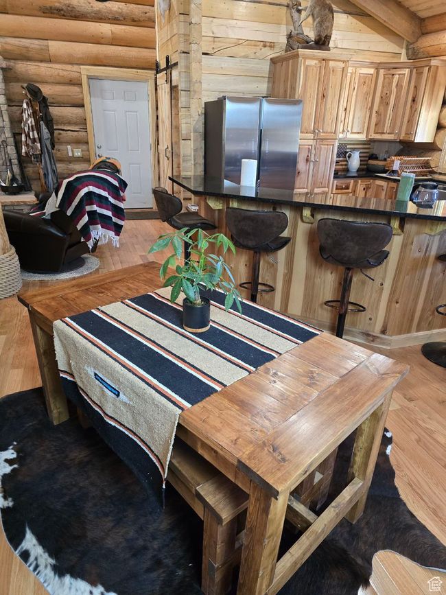 Dining space featuring beamed ceiling, light wood-style flooring, log walls, and a barn door | Image 63