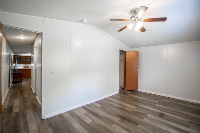 Unfurnished room featuring ceiling fan, dark wood finished floors, and lofted ceiling | Image 24