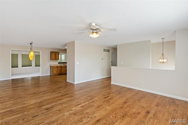 Unfurnished living room featuring wood finished floors, baseboards, and ceiling fan | Image 5