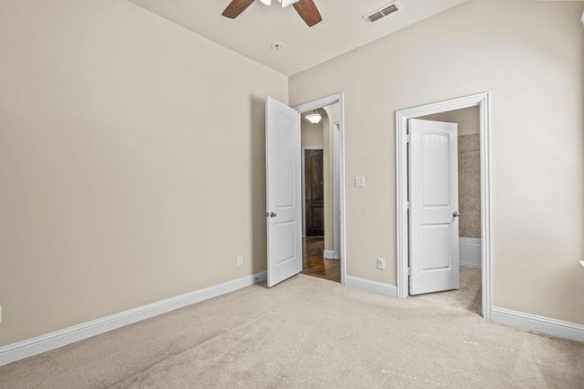 Unfurnished bedroom with carpet floors, connected bathroom, baseboards, and ceiling fan | Image 8