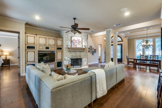 Living area with crown molding, ceiling fan, a fireplace, baseboards, and dark wood-style flooring | Image 4