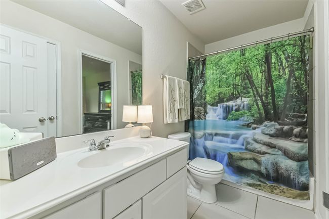 The guest bath features a large mirror, single sink, a shower-tub combo and neutral tile flooring. | Image 27