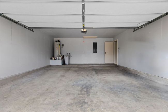 Garage featuring electric panel, water heater, and a garage door opener | Image 27