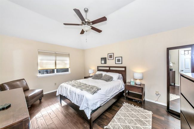 Bedroom with dark wood-type flooring, baseboards, lofted ceiling, and ceiling fan | Image 18