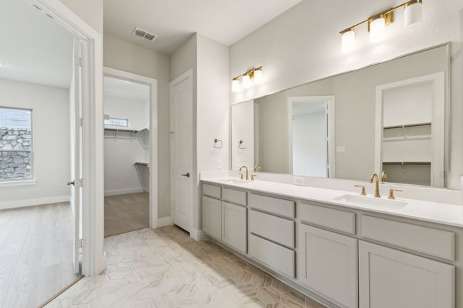 Full Primary bathroom with double vanity, a walk in closet, and marble look tiles | Image 4