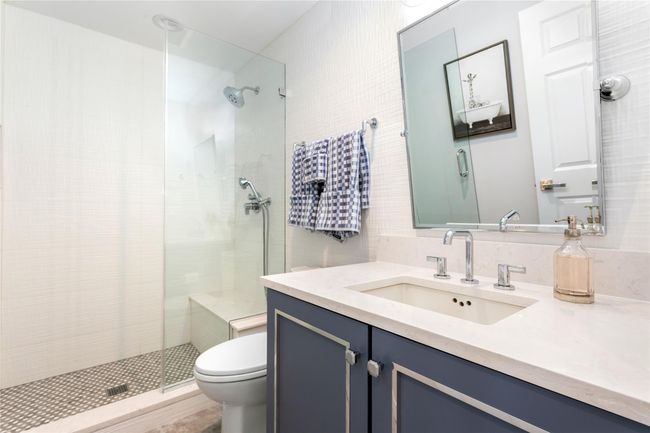 Bathroom featuring toilet, a shower stall, tile walls, and vanity | Image 18