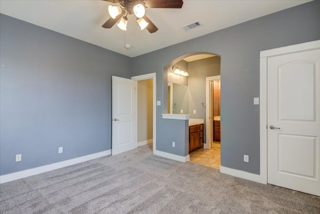 Secondary bedroom featuring light carpet, ensuite bath, and arched walkways | Image 26