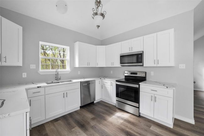 Kitchen featuring stainless steel appliances, dark wood-style flooring, and white cabinets | Image 8