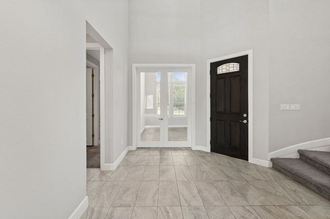 Entrance foyer featuring a high ceiling, stairway, marble finish floor, baseboards, and french doors | Image 6