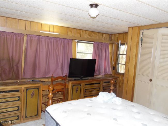 Bedroom featuring a closet and wood walls | Image 10