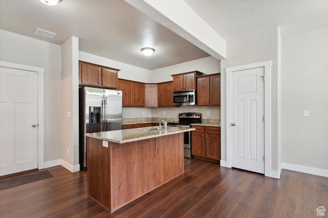 Kitchen with appliances with stainless steel finishes, a sink, dark wood finished floors, and light stone counters | Image 10