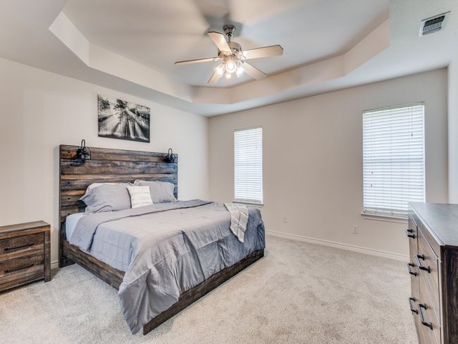 Bedroom featuring light colored carpet, a raised ceiling, baseboards, and a ceiling fan | Image 18