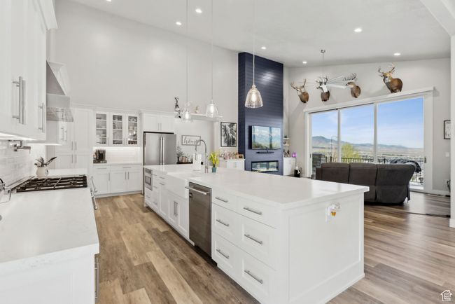 Kitchen featuring recessed lighting, appliances with stainless steel finishes, light countertops, wall chimney exhaust hood, and a towering ceiling | Image 51