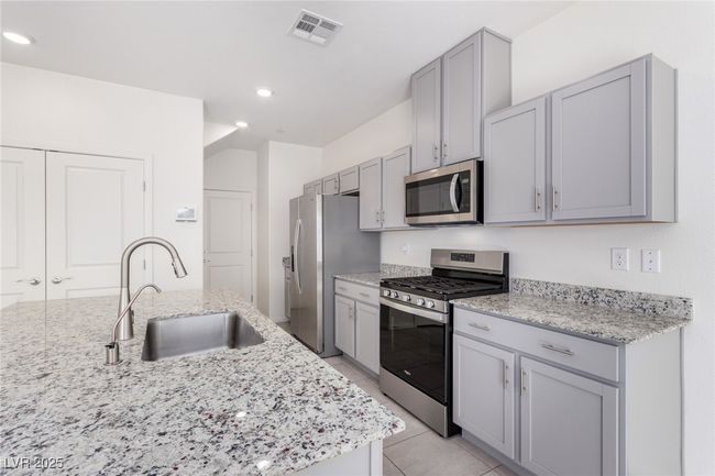Kitchen with a sink, visible vents, gray cabinetry, and stainless steel appliances | Image 9