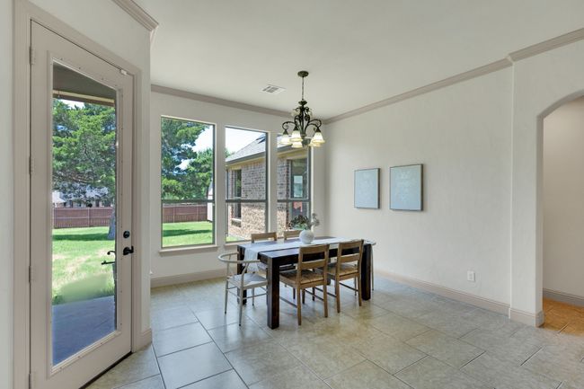 Dining space with arched walkways, crown molding, healthy amount of natural light, a chandelier, and light tile patterned floors | Image 7