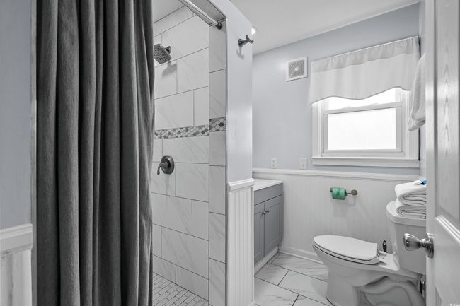 Full bath with marble finish floors, toilet, wainscoting, vanity, and a stall shower | Image 10