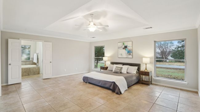 Bedroom with crown molding, light tile patterned floors, baseboards, a raised ceiling, and visible vents | Image 23