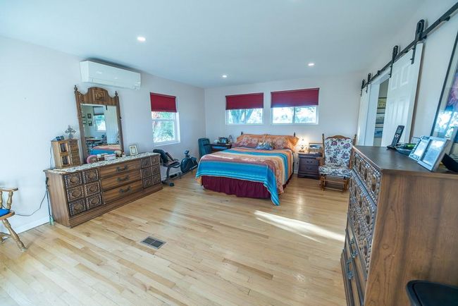 Bedroom with light hardwood / wood-style flooring, a barn door, and a wall unit AC | Image 11