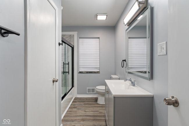 full bath with toilet, vanity, wood finished floors, baseboards, and enclosed tub / shower combo | Image 24