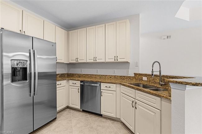 Kitchen featuring appliances with stainless steel finishes, dark stone countertops, a peninsula, and light tile patterned flooring | Image 7