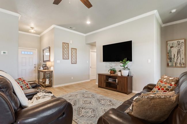 Living area with ceiling fan, light wood-style flooring, and ornamental molding | Image 8