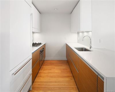 Kitchen with stainless steel appliances, sink, white cabinetry, and light hardwood / wood-style floors | Image 3