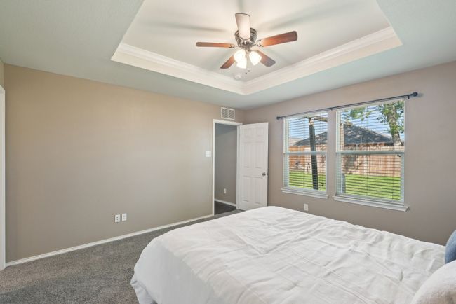 Bedroom featuring visible vents, crown molding, baseboards, a raised ceiling, and carpet floors | Image 24