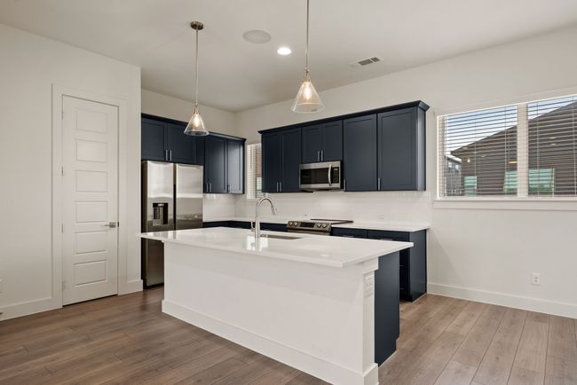 Kitchen with a healthy amount of sunlight, stainless steel appliances, light countertops, and light wood-style floors | Image 17