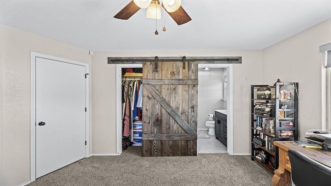 Office area featuring a ceiling fan, carpet, and a barn door | Image 44