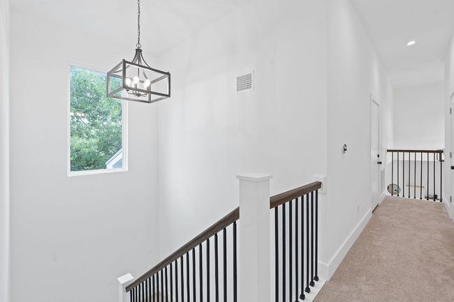 Hall with a healthy amount of sunlight, carpet floors, visible vents, and an upstairs landing | Image 30