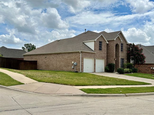 View of property exterior with brick siding, driveway, and roof with shingles | Image 24