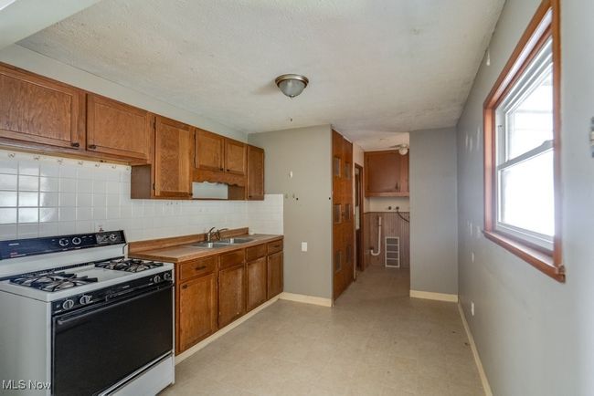 Kitchen featuring range with gas cooktop, a sink, brown cabinetry, tasteful backsplash, and light floors | Image 15