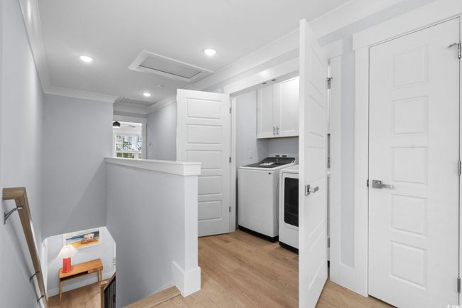Laundry area with ornamental molding, light wood finished floors, cabinet space, recessed lighting, and washing machine and clothes dryer | Image 15