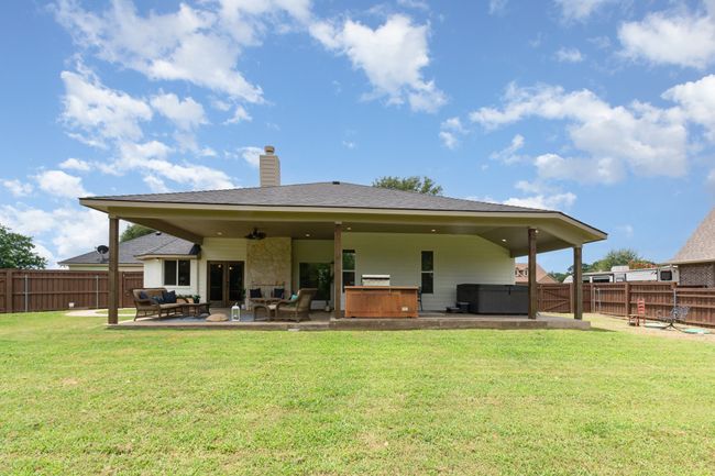 Rear view of house featuring an outdoor living space, a fenced backyard, a hot tub, a chimney, and a patio area | Image 33