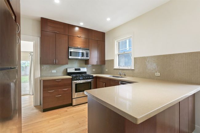 Kitchen featuring appliances with stainless steel finishes, a peninsula, light wood finished floors, light countertops, and recessed lighting | Image 4