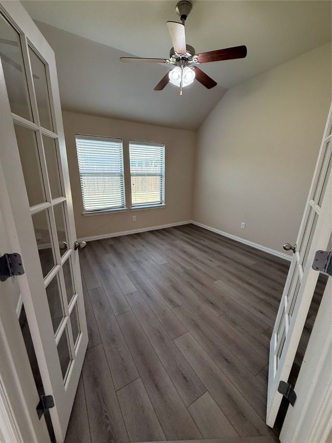 Empty room featuring dark wood-type flooring, baseboards, a ceiling fan, and lofted ceiling | Image 8