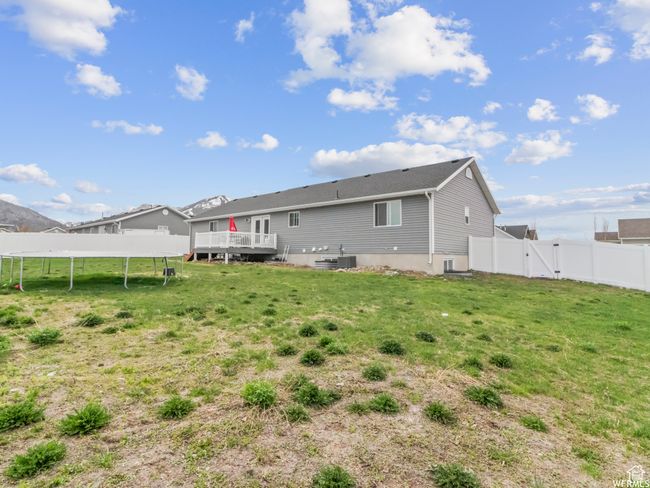 Rear view of house with a gate, a trampoline, a deck, and central AC | Image 23