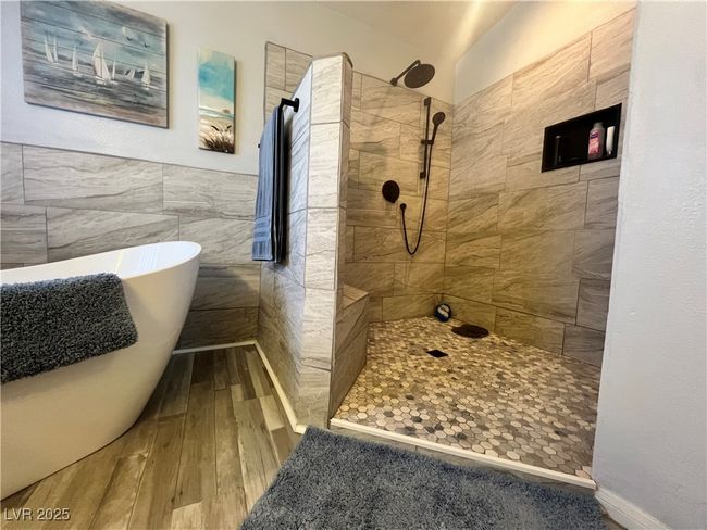 Bathroom with wood-type flooring, a walk in shower, a freestanding tub, and tile walls | Image 41