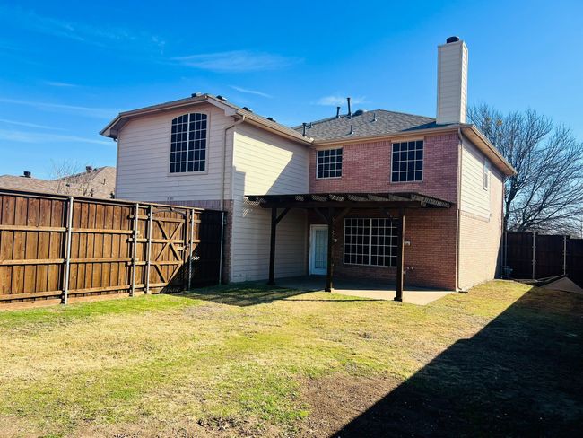 Back of property with brick siding, a chimney, a lawn, a patio area, and a fenced backyard | Image 24